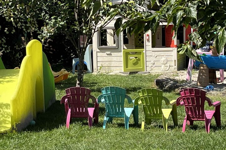 Petras Garten mit Spielhaus, Rutsche und bunten Kinderstühlen.